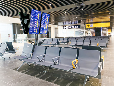 Empty airport departure lounge with seating and flight information display system