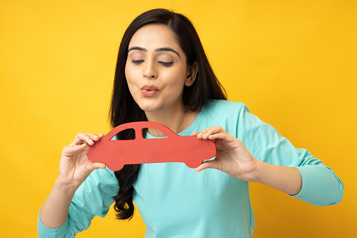Photo of cheerful girl holding paper car with hands isolated yellow background