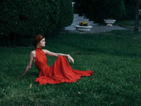 woman in red dress sitting on the lawn in the garden fantasy decoration. High quality photo