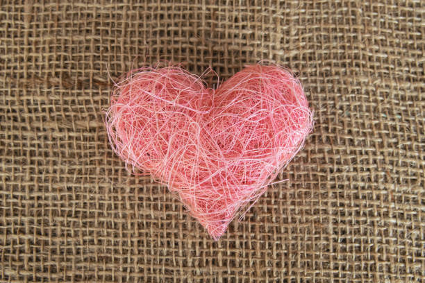 Heart shape made of pink material fabric on a rustic natural background with copyspace. Concept of Valentine's day and romantic love.
