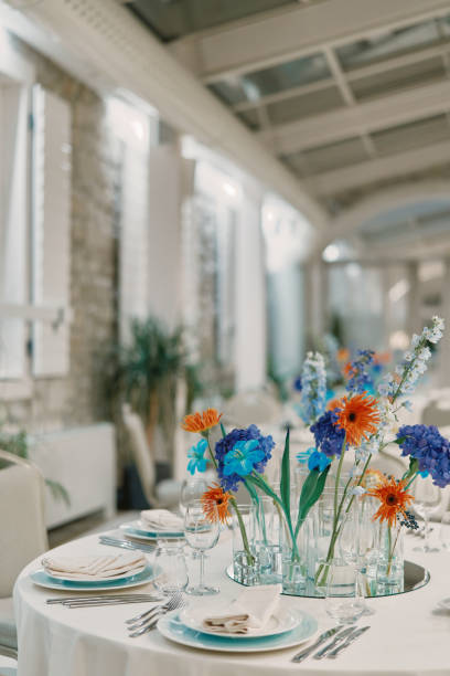 istock Colorful flowers in vases stand on a set table in a restaurant 2034990691