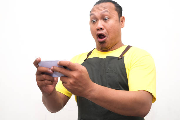 Adult Asian man showing shocked face expression while looking to his mobile phone