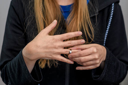 A woman takes off a silver wedding ring from her finger, separation and divorce