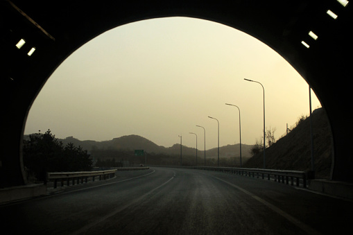 Chengde, China - 07 April, 2011: A car is driving through a tunnel towards the exit. Sunlight beams in, signaling the end of the tunnel. There's very little traffic, making for a peaceful drive.