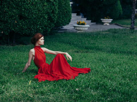 woman in red dress sitting on the lawn in the garden fantasy decoration. High quality photo