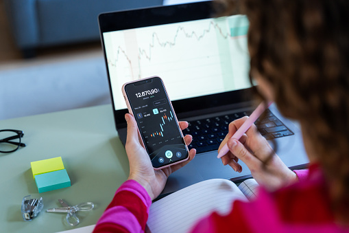 Curly-haired woman checking stock market on smartphone