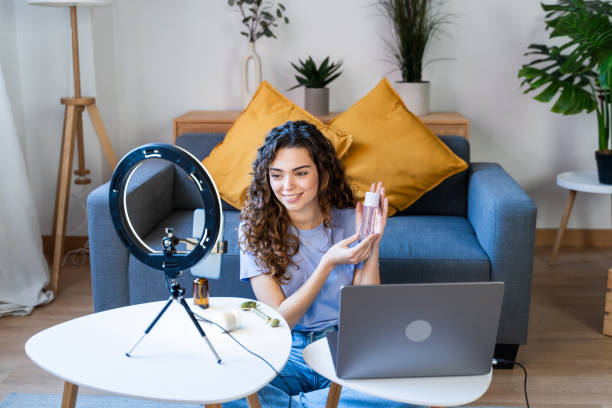 Online Beauty Influencer Presenting Products Curly-haired woman showcasing skincare products on camera product review stock pictures, royalty-free photos & images