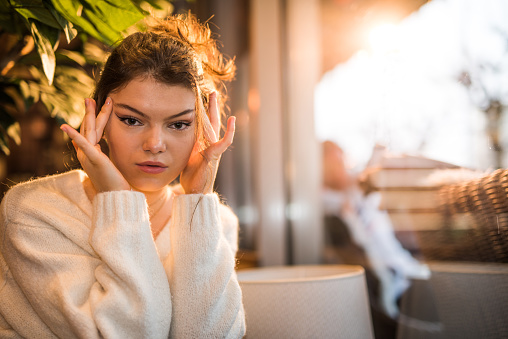 Girl getting a massage after hard studying, tired from studying brown-haired in a white sweater in the cafeteria