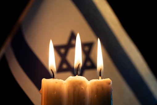 Burning candles with Israel flag on background
