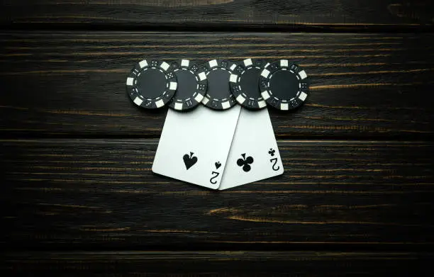 Photo of A gambling and popular poker game with a winning combination of one pair. Chips and cards on a dark vintage table in a poker club