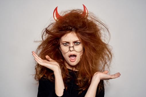 Brunette in a devil costume on Halloween red horns glasses black dress. High quality photo