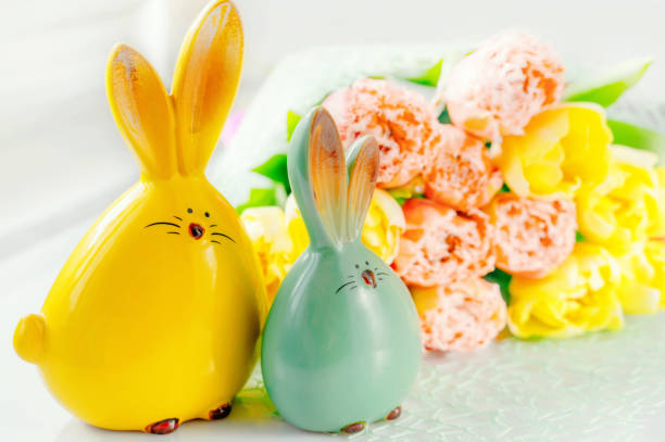 Easter bunny figures in an Easter composition. Yellow and red tulips with Easter bunnies in the foreground.