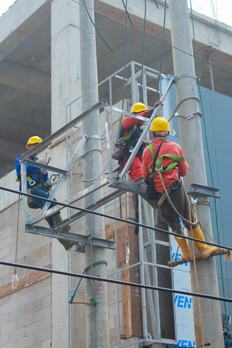 Several electricians are repairing electricity poles.