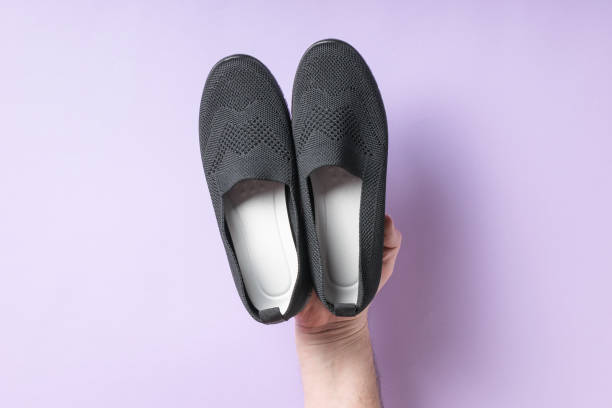 A man's right hand holding a woman's rag shoes.