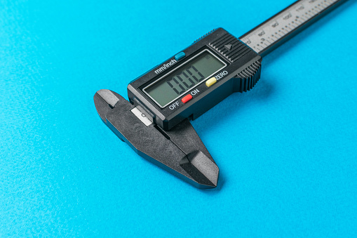 Electronic caliper close-up on a blue background. A tool for accurate measurement of dimensions.