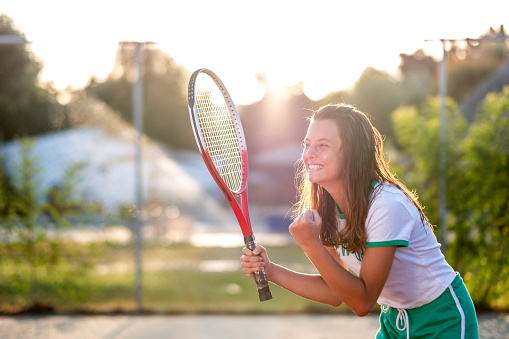 beautiful teenage girl enjoys playing tennis, looking forward to winning a point
