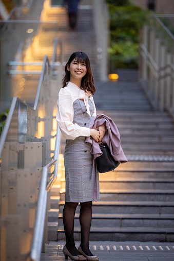 Portrait of happy business woman standing on stairs in urban city