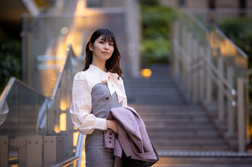 Portrait of confident business woman standing on stairs in urban city