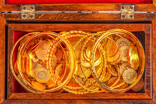 Open treasure chest full of golden coins on sandy beach. Wealth and treasure concept. 3d illustration