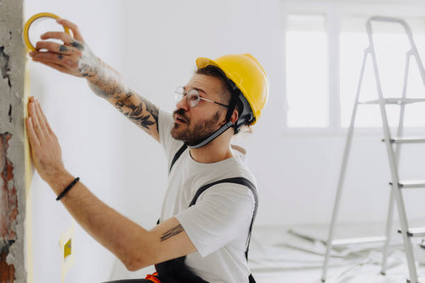 istock Man putting tape on the wall. The simple step for the quick and easy painting process. Renovation house concept 2035243178