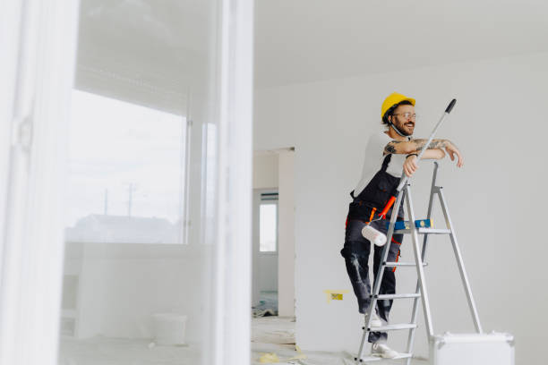 istock Handyman with roller on step ladder in room. Ceiling painting 2035244932