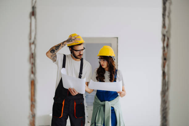 istock Man and woman construction workers in protection gear holding documents ant talking on indoor building construction site 2035250577