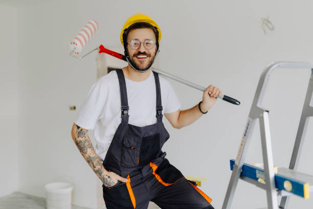 istock Handyman with roller on step ladder in room. Ceiling painting 2035251697