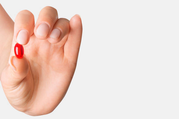 istock Female hand holding a red pill on a light background 2035258345