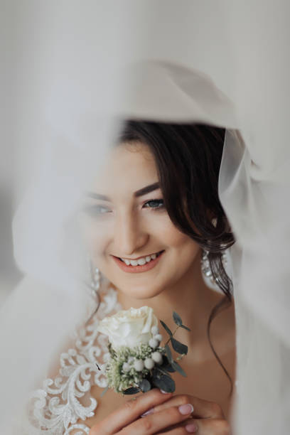 istock A brunette bride in a white dress holds her wedding bouquet 2035270549