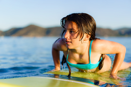Teenage girl surfing on a board at the sea