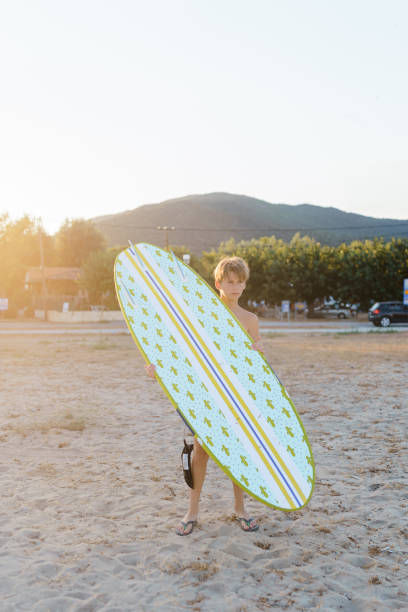 istock Teenage boy holding a surfboard at the beach 2035297952