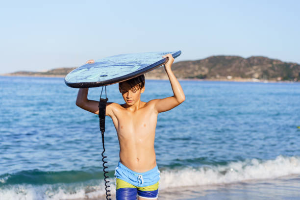 istock Teenage boy holding a surfboard at the beach 2035298534