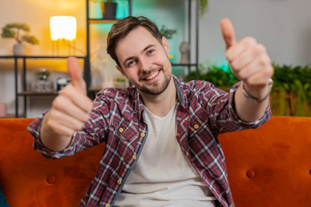 istock Happy man looking approvingly at camera showing double thumbs up like sign positive feedback at home 2035305585