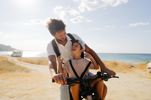 Father and son exploring the coastline on a bicycle