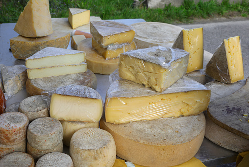 aged cheese wheels and fresh cheese chunks for sale at a market stall