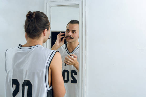 rear view of gender non-binary person standing in front of mirror - contreras zdjęcia i obrazy z banku zdjęć