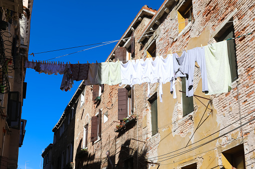 many clothes hanging and linen drying in the sun in the narrow alley between the houses