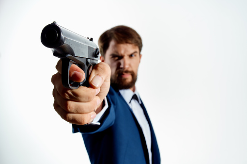 bearded man in suit gun close up killer murder light background. High quality photo