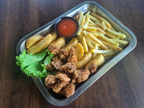 Serving Of A Snack Platter On Tray With French Fries, Potato Wedges, Chicken Pop And Mix Salad. Food Menu.