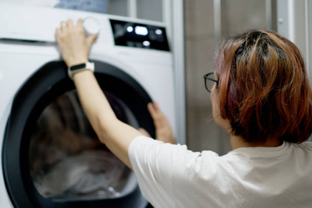 istock Female hand choose mode with knob on washing machine indoors 2035353200