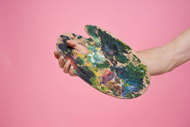 istock Artist's hand paints palette easel for drawing training pink background 2035354168