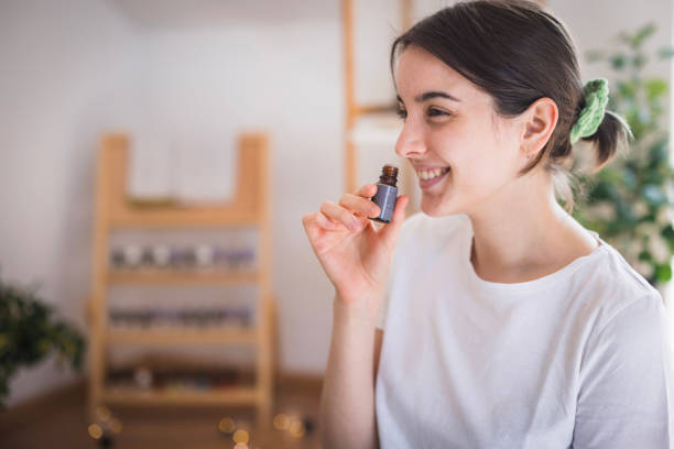 Smiling young woman smeling essential oil
