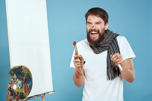 Male artist easel art drawing creativity blue background. High quality photo