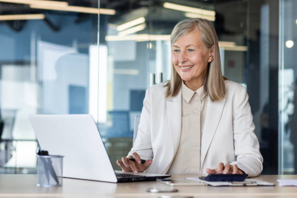 istock Senior businesswoman smiling while working at laptop in modern office setting, exuding confidence and professionalism 2035363120