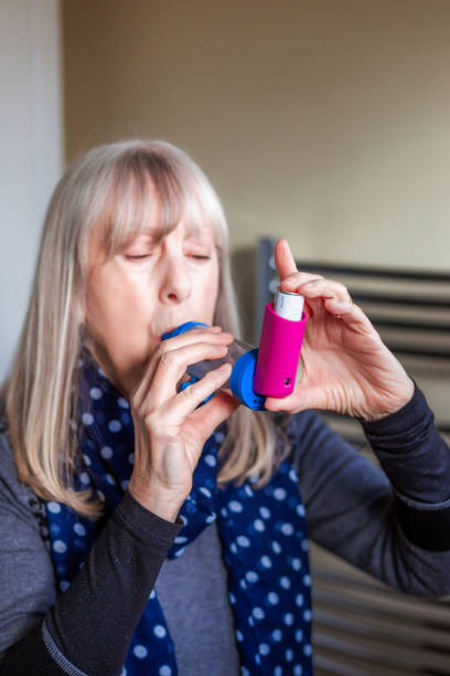 istock Asthmatic senior woman using asthma inhaler at home 2035363124