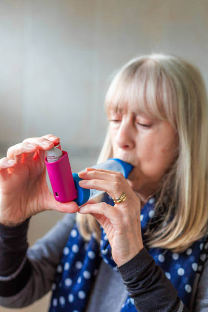 istock Asthmatic senior woman using asthma inhaler at home 2035363161