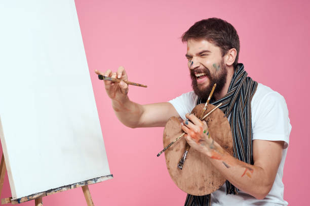 istock painter holding palette drawing art easel hobby creativity pink background 2035367016