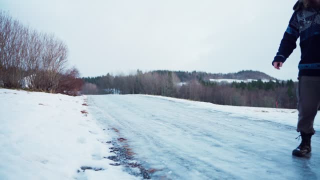 A Man is Attempting to Walk on a Slippery, Icy Road - Static Shot