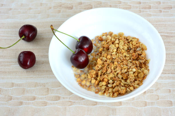 granola with milk and cherries in bowl top view