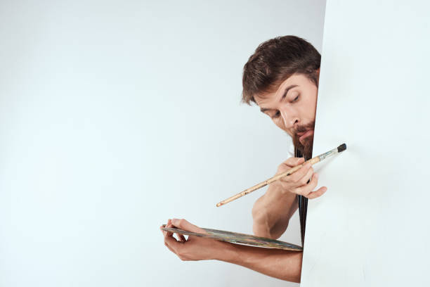 Male artist hiding behind an easel palette drawing art. High quality photo